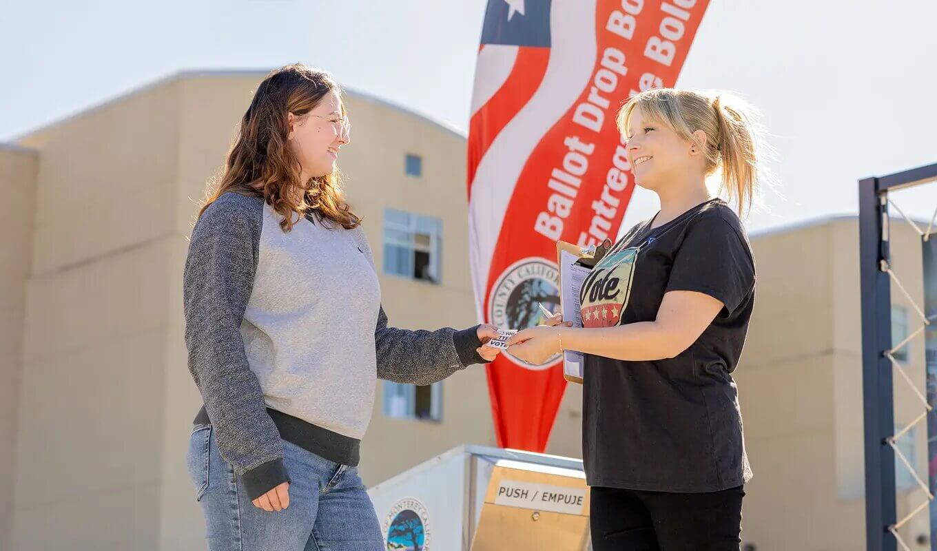 a university employee handing a student voting materials