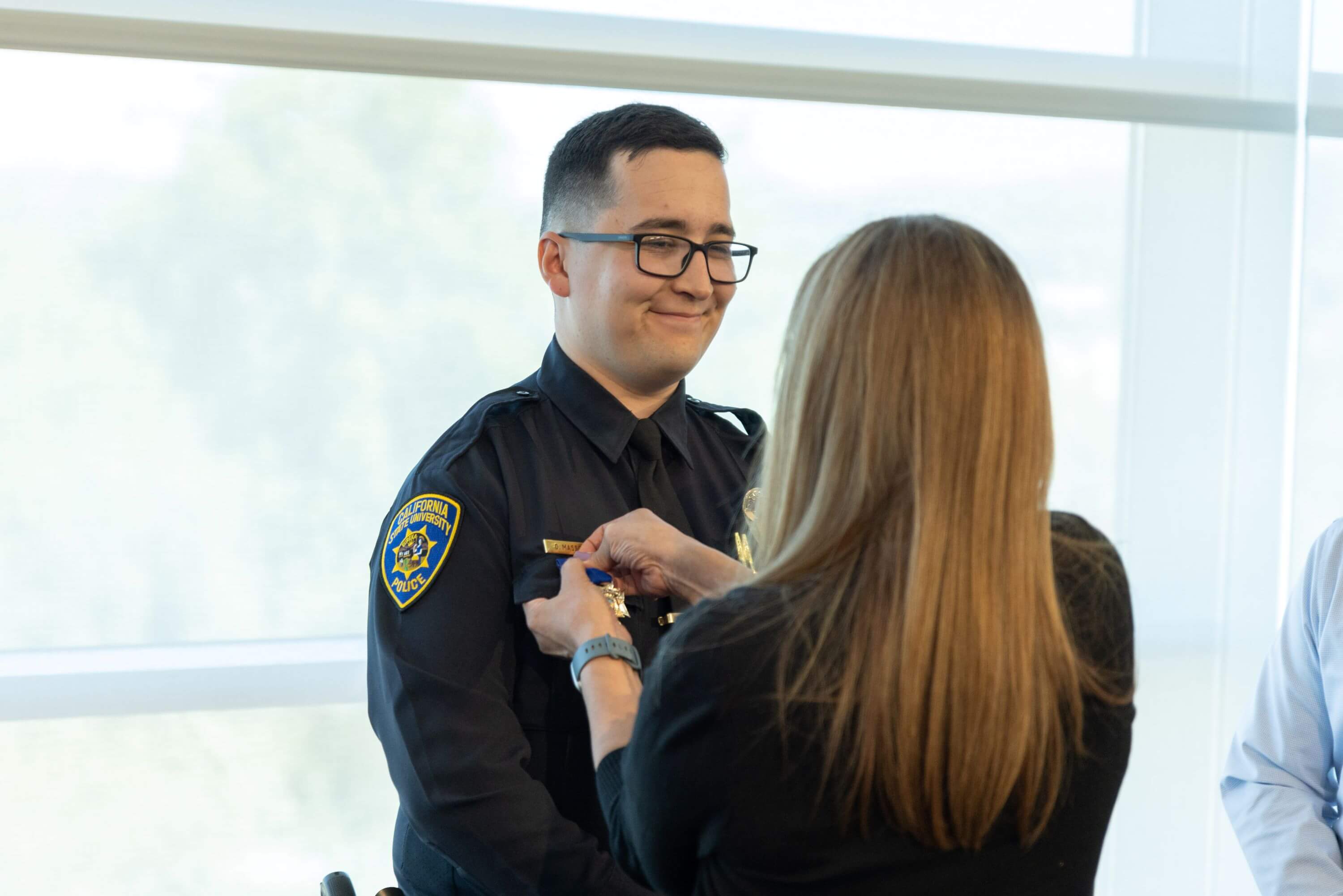 an individual pins a medal on officer david massons uniform