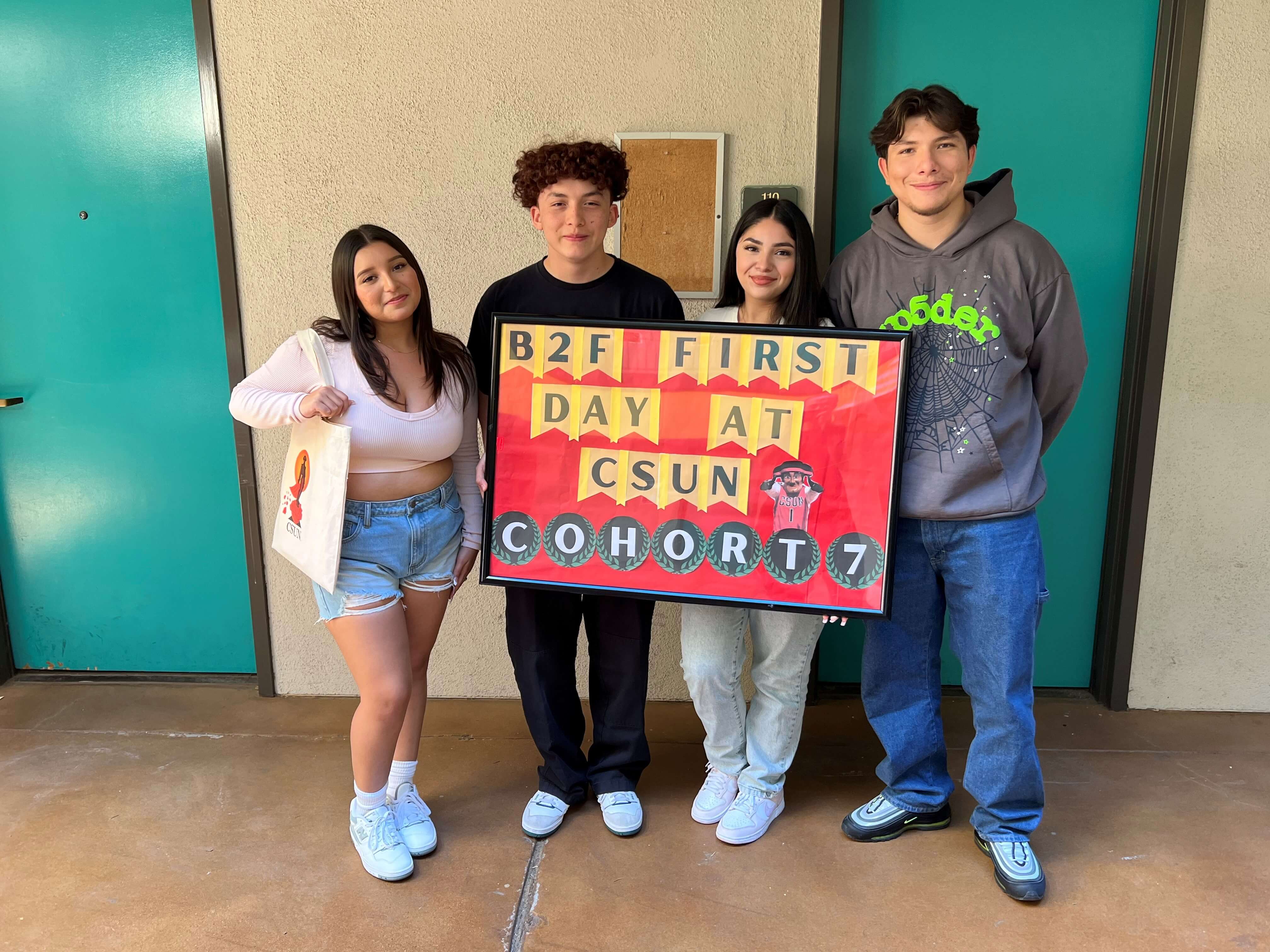 college students holding a sign that says first day