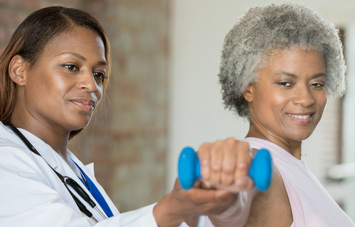 Female Physical Theripst helping a woman hold up a weight