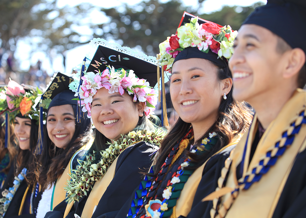 A row of Monterey Bay students at their graduation wearing their capsand gowns.