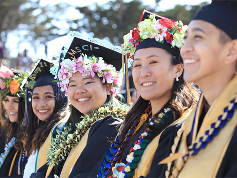 A row of Monterey Bay students at their graduation wearing their capsand gowns.