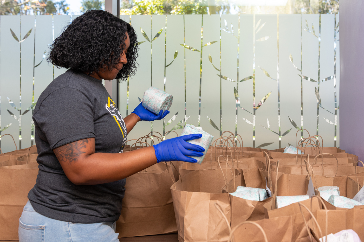 CSUDH employee places roll of toilet paper in care packages.