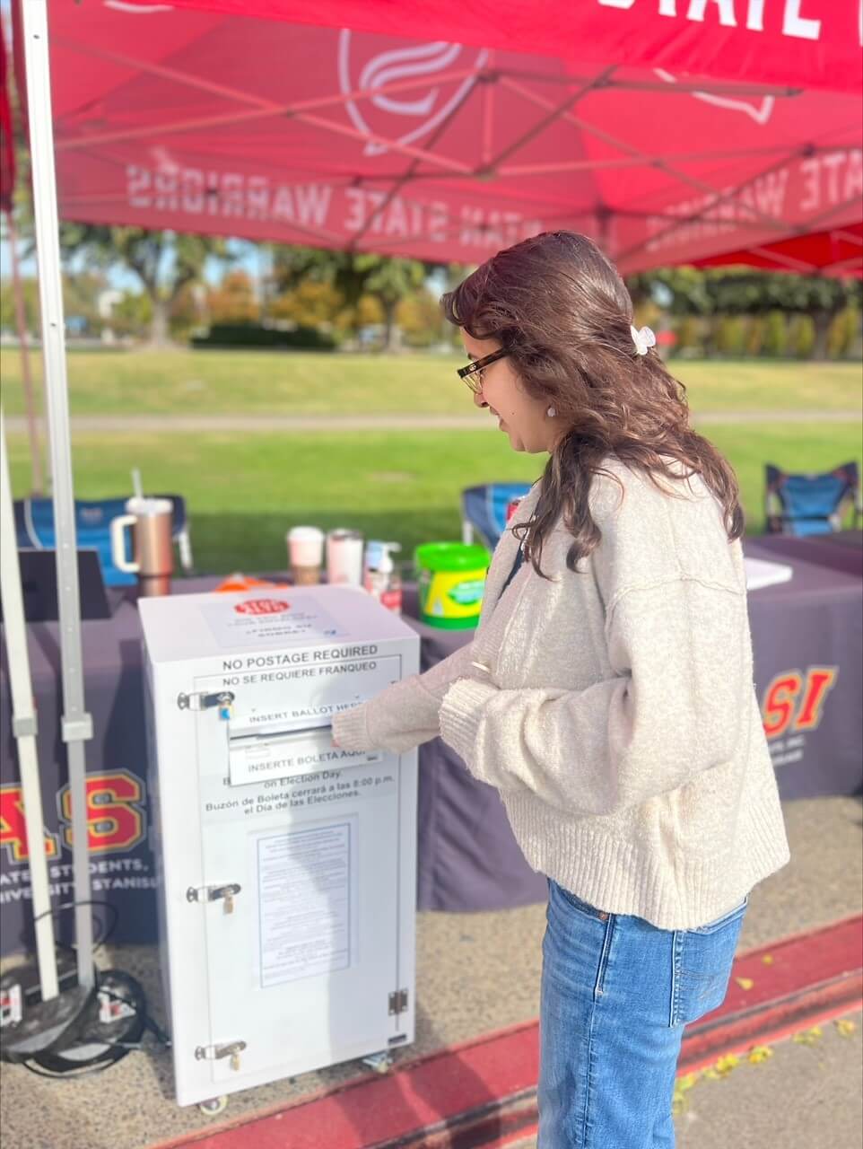 student dropping ballot in box