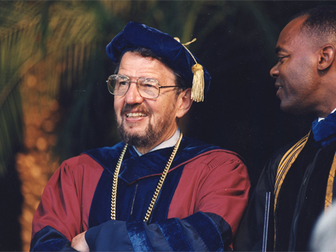 Former San Francisco State President Robert Corrigan smiling at a commencement ceremony.