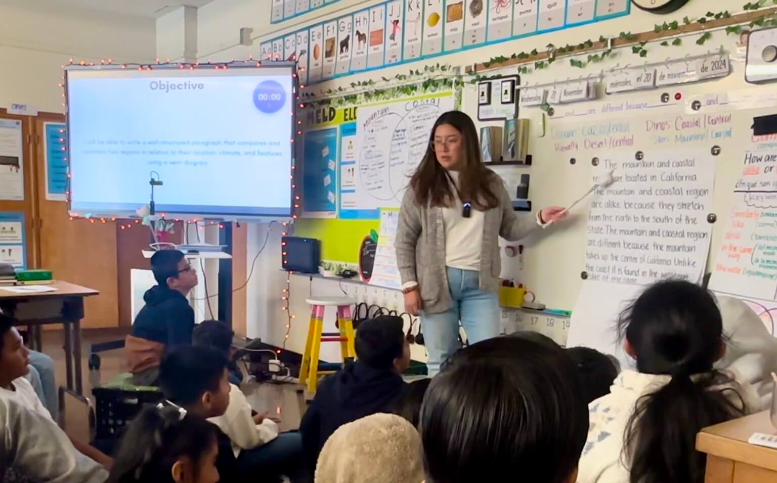 A teacher residency student at the whiteboard in front of young students