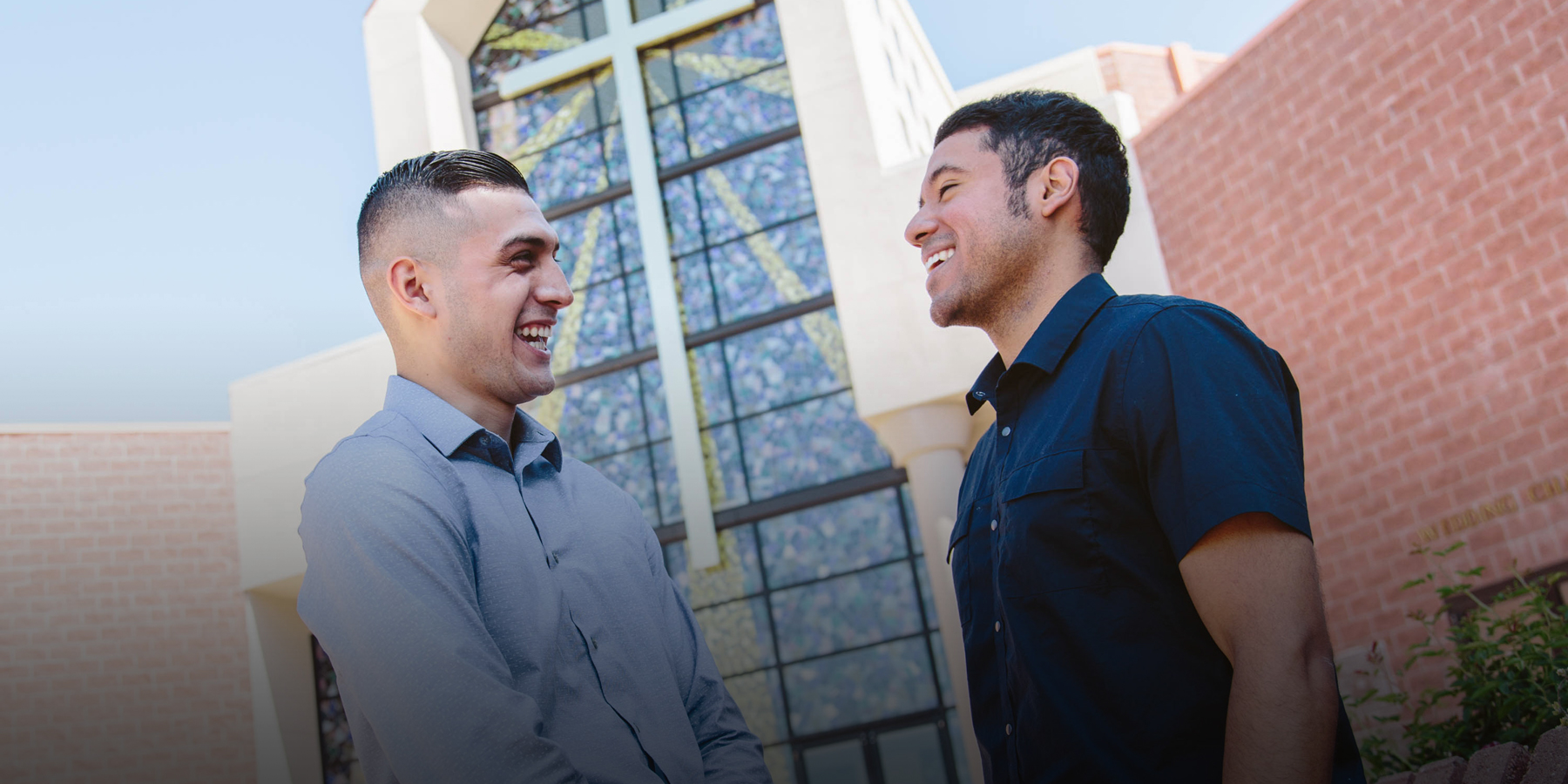 Anthony laughs with his pastor in front of a church.