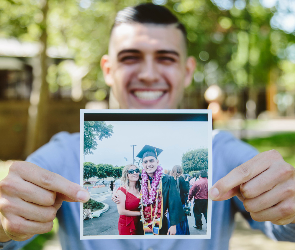 Anthony holds up a photo from his graduation with his mother.