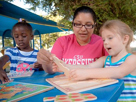 teacher with young children building a puzzle